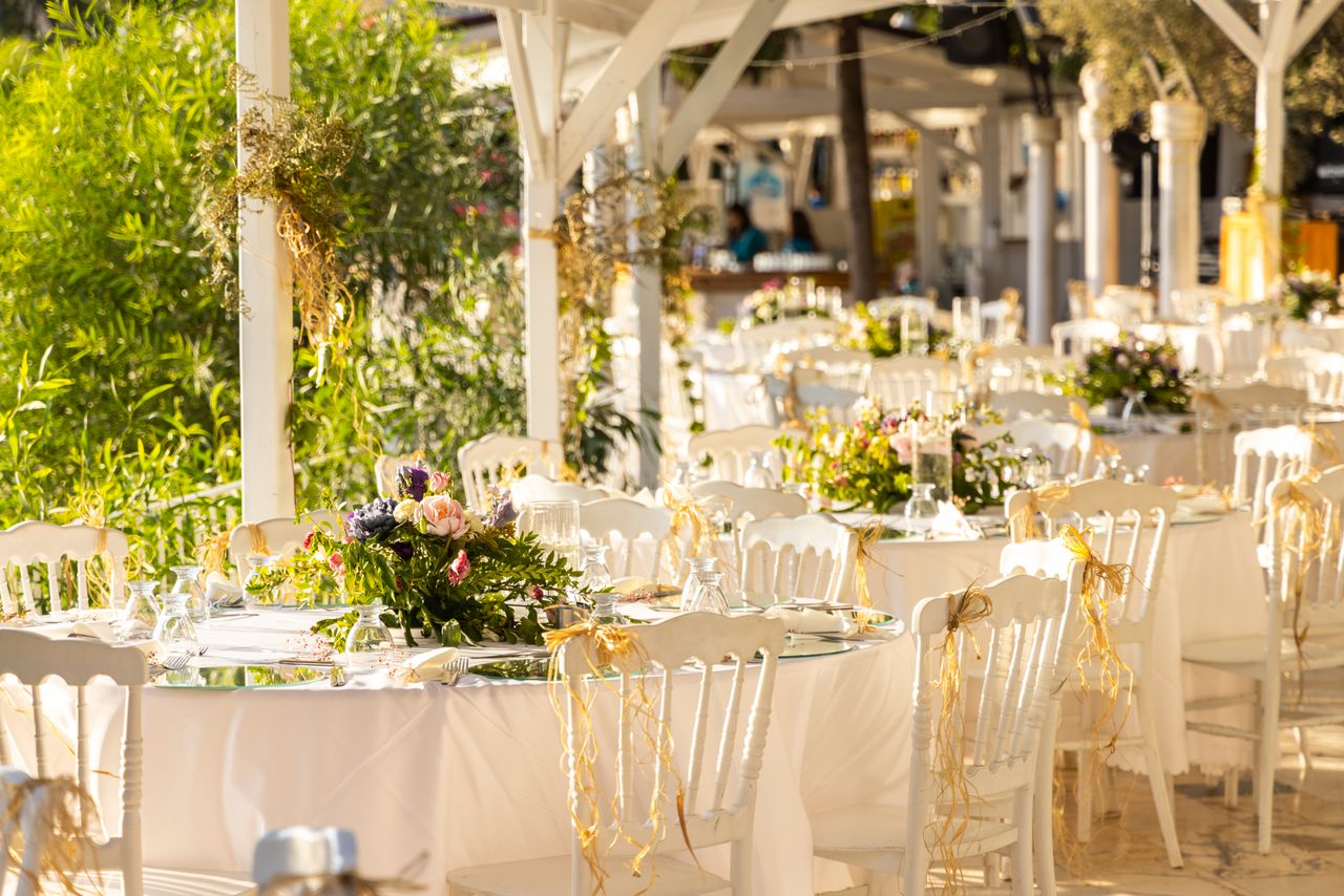 get-in-touch Beautifully arranged outdoor wedding reception with floral centerpieces and white decor.